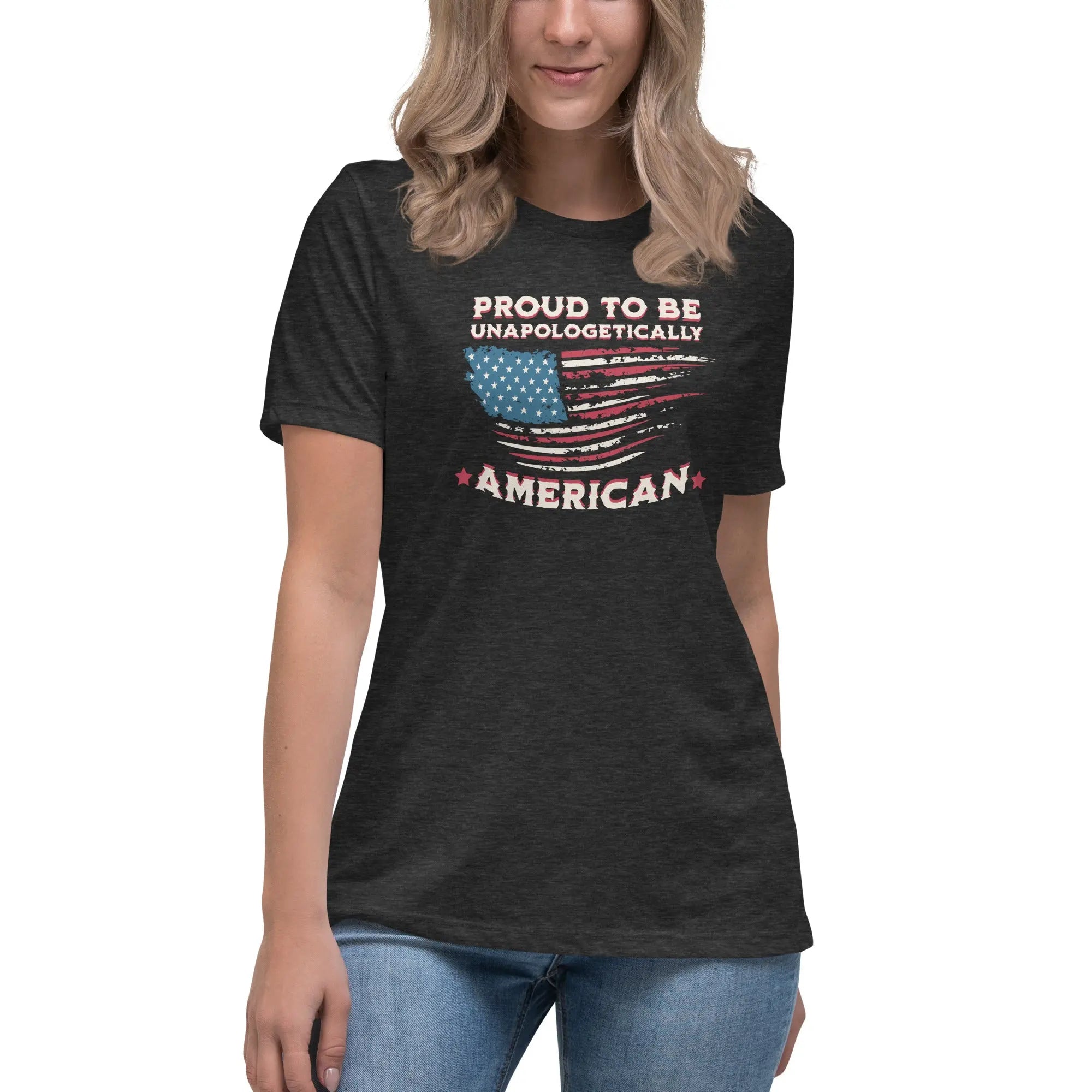 A woman wearing a dark grey heather patriotic t-shirt with the American flag and "Proud To Be Unapologetically American" text.