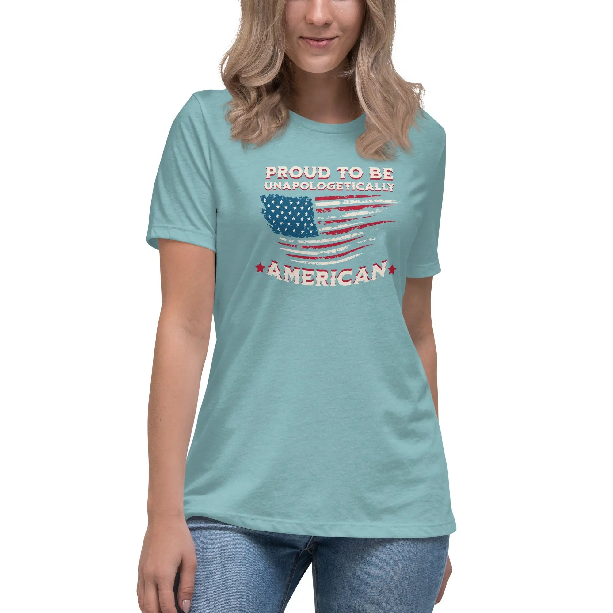 A woman wearing a heather blue lagoon patriotic t-shirt with the American flag and "Proud To Be Unapologetically American" text.