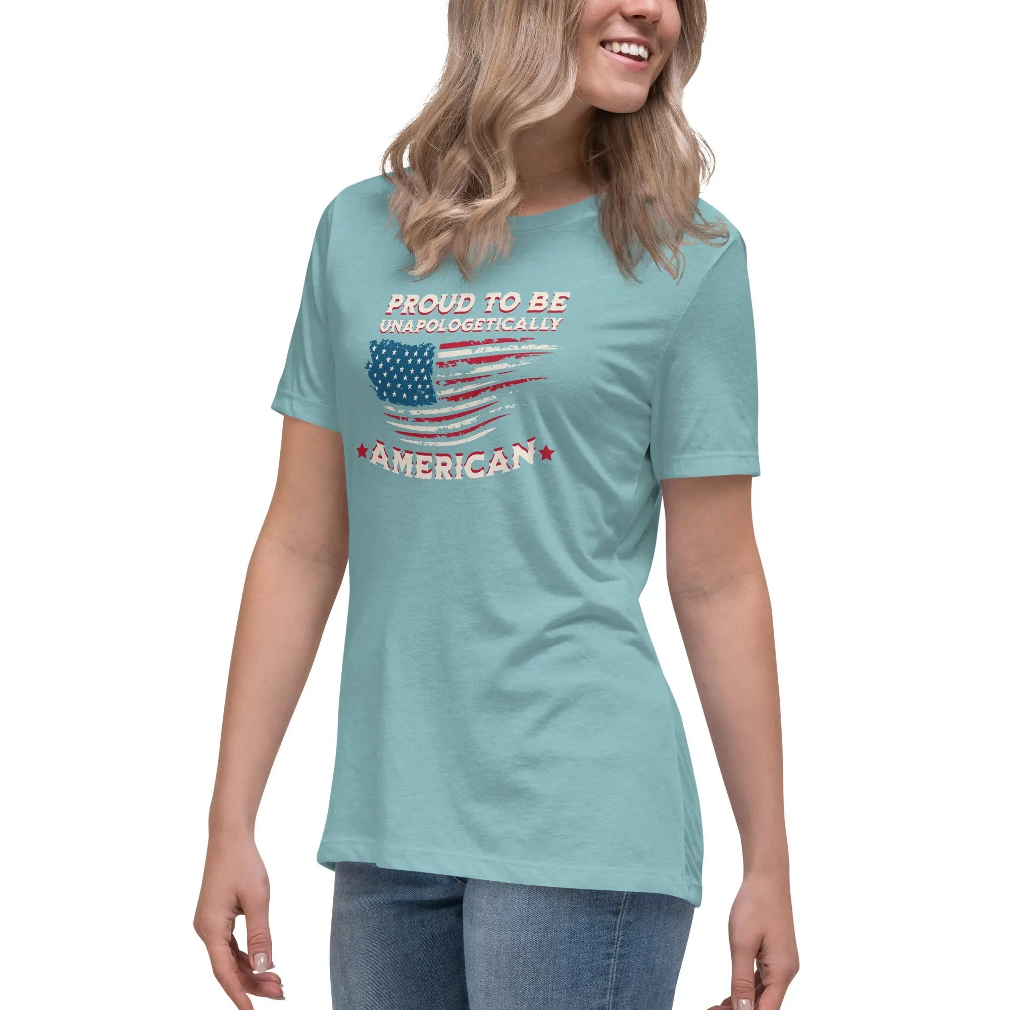 A woman wearing a heather blue lagoon patriotic t-shirt with the American flag and "Proud To Be Unapologetically American" text.