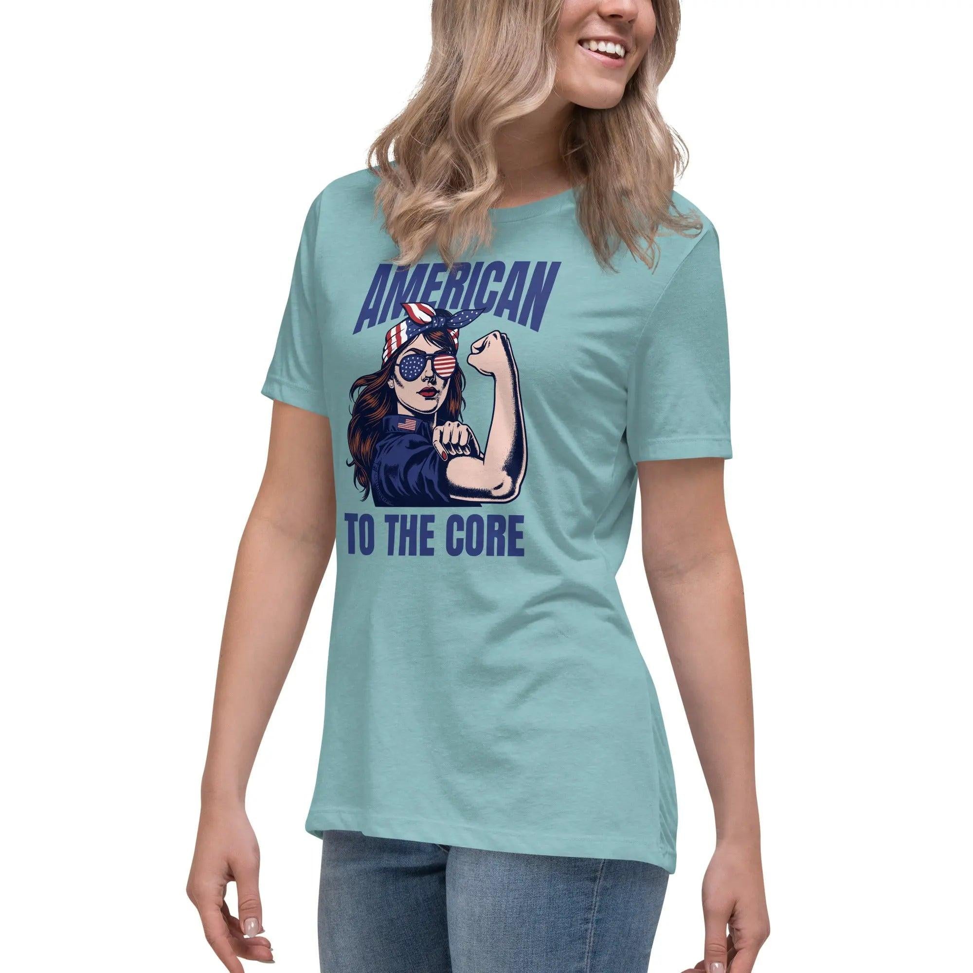A woman wearing a heather blue lagoon, patriotic t-shirt with a strong woman and "American To The Core" text.