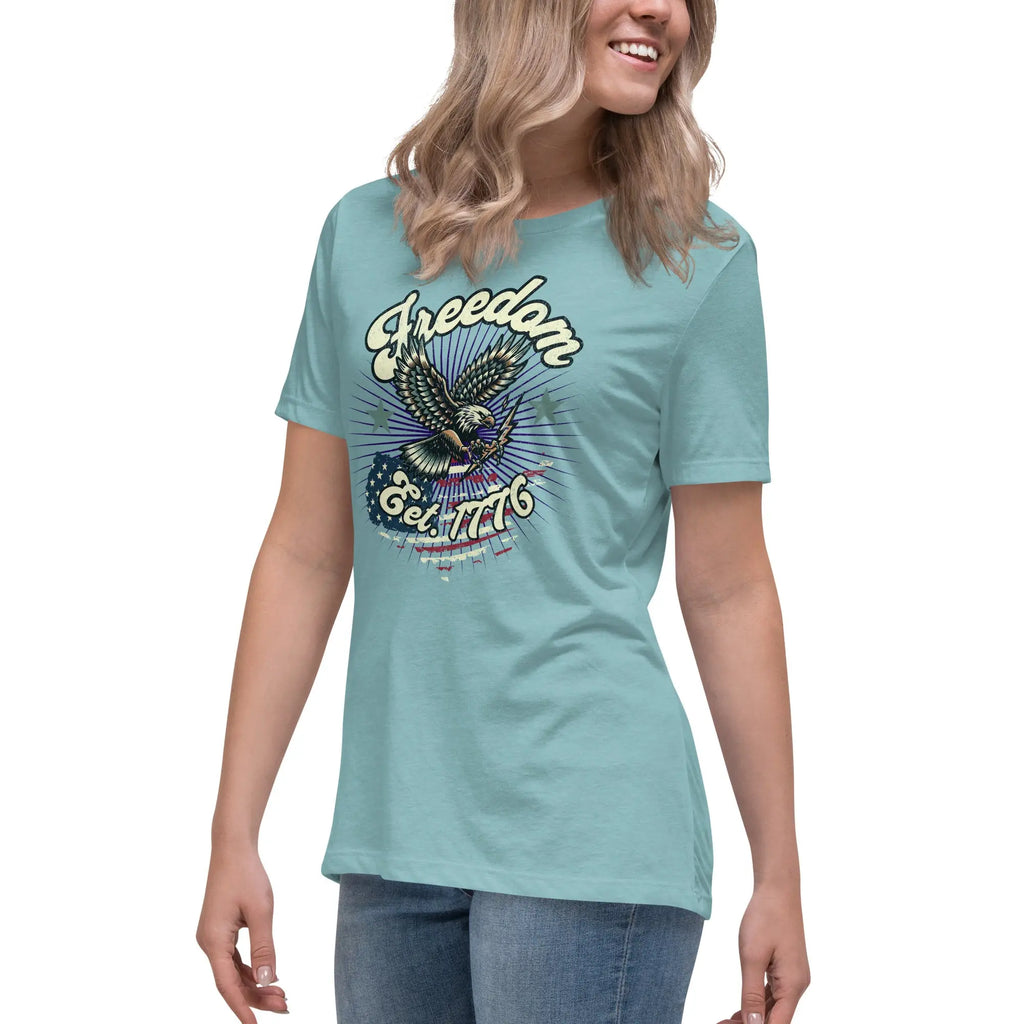 A woman wearing a heather blue patriotic t-shirt with an eagle and "Freedom Est. 1776" text.