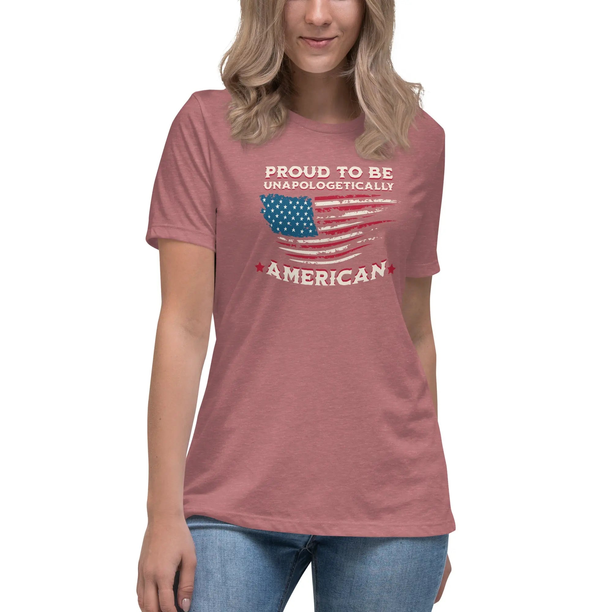 A woman wearing a heather manuve patriotic t-shirt with the American flag and "Proud To Be Unapologetically American" text.
