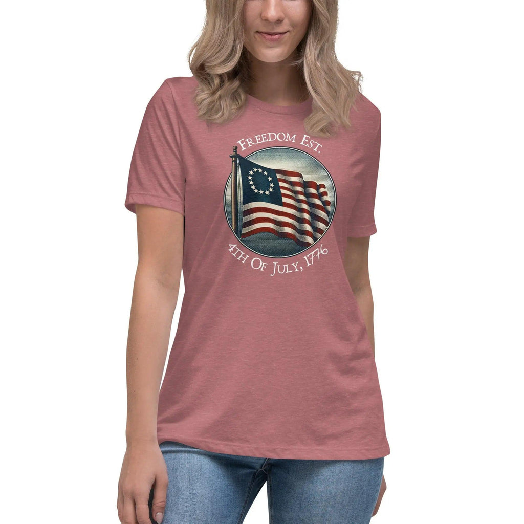 A woman wearing a heather mauve patriotic t-shirt with the American flag and the text "Freedom est. 4th of July, 1776."