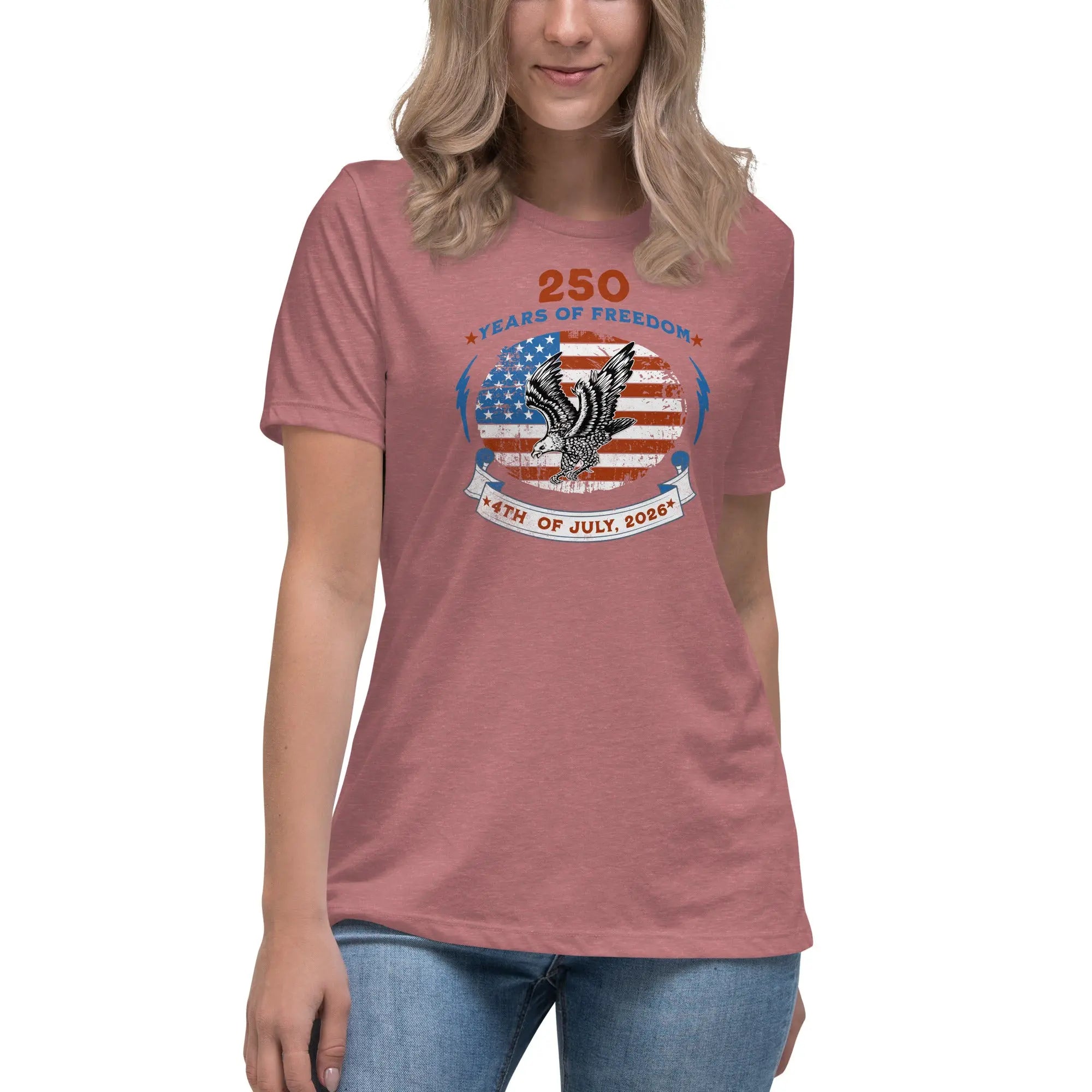 A woman wearing a heather mauve patriotic t-shirt with the American flag with a flying eagle over it and the text "250 years of freedom 4th of July, 2026."