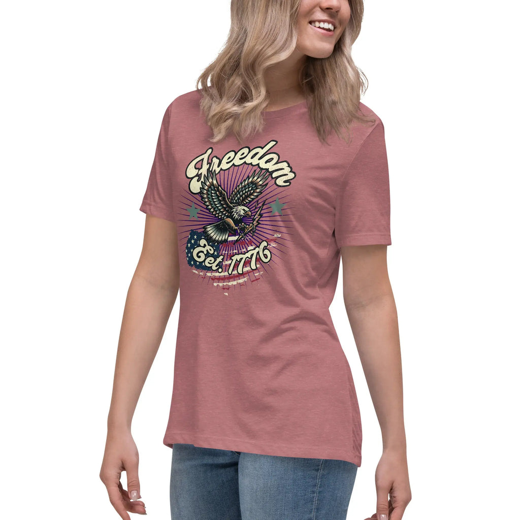 A woman wearing a heather mauve patriotic t-shirt with an eagle and "Freedom Est. 1776" text.