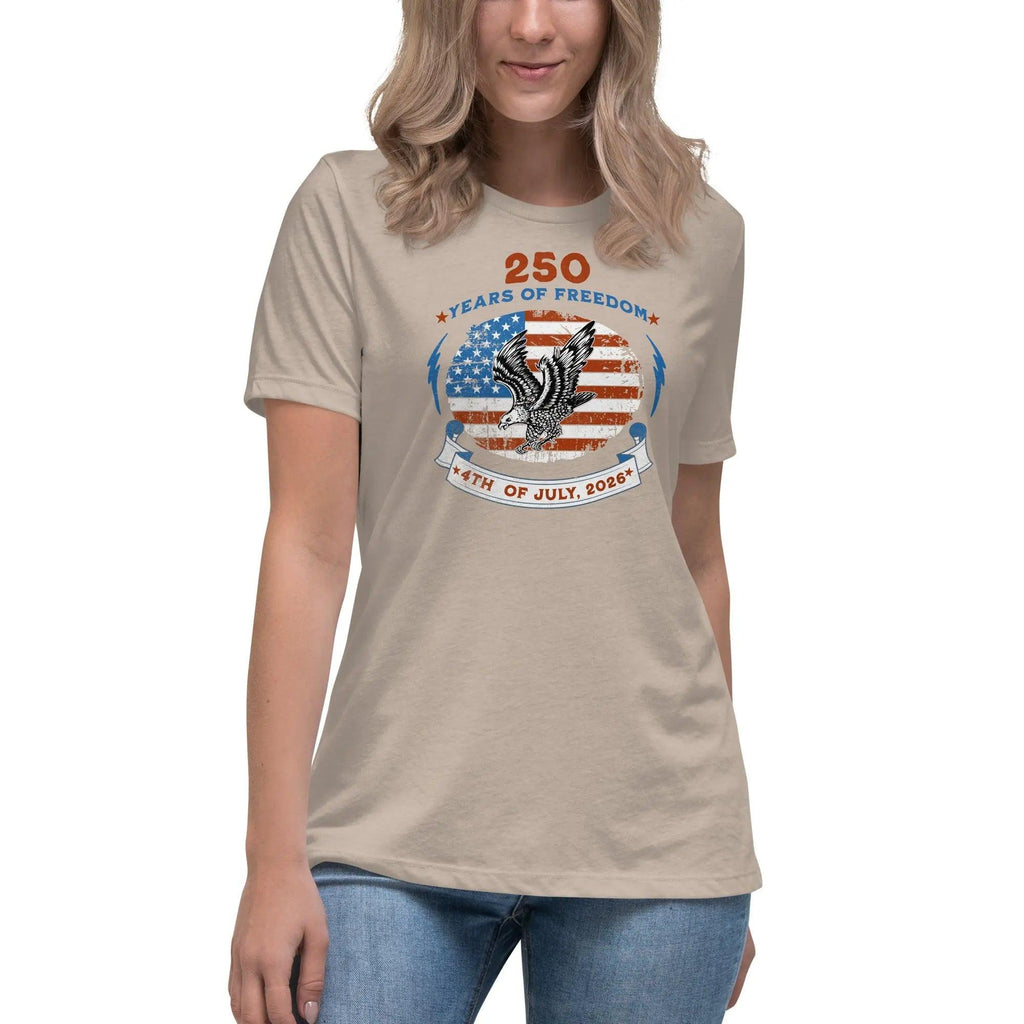 A woman wearing a heather stone patriotic t-shirt with the American flag with a flying eagle over it and the text "250 years of freedom 4th of July, 2026."