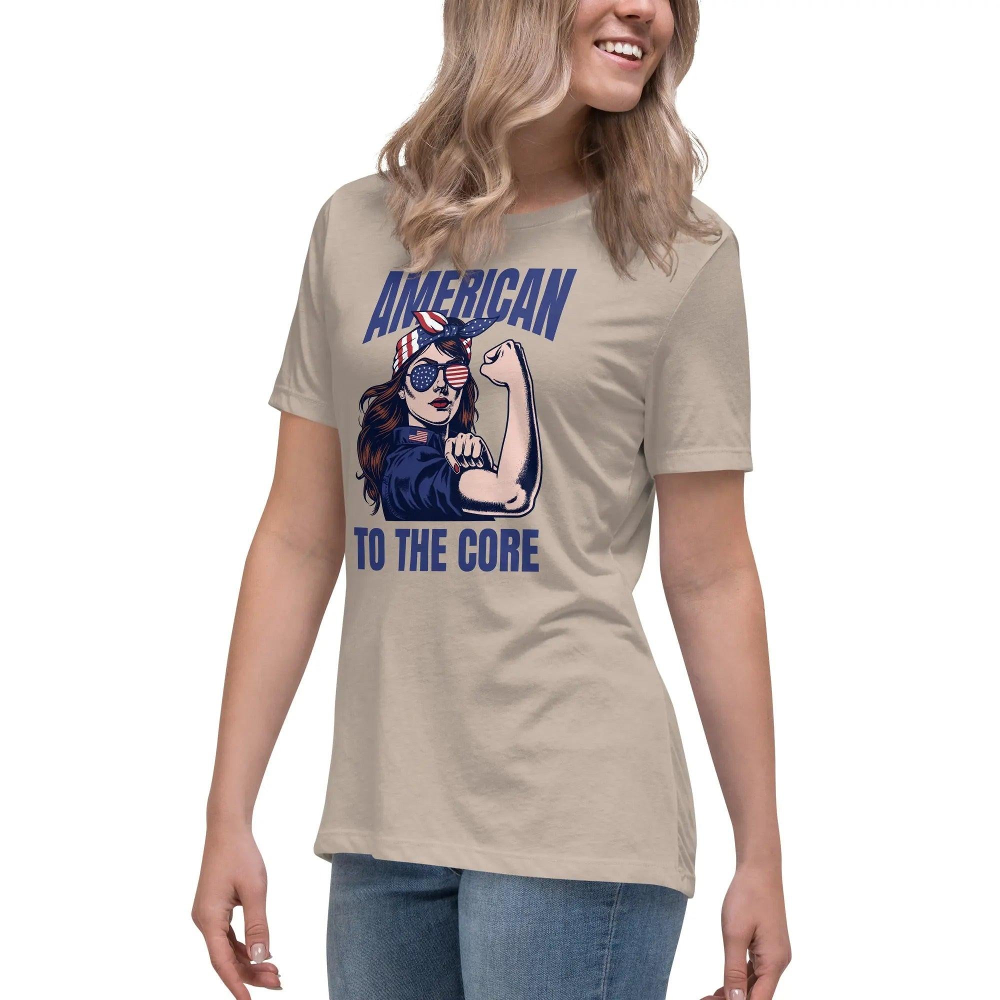 A woman wearing a heather stone, patriotic t-shirt with a strong woman and "American To The Core" text.